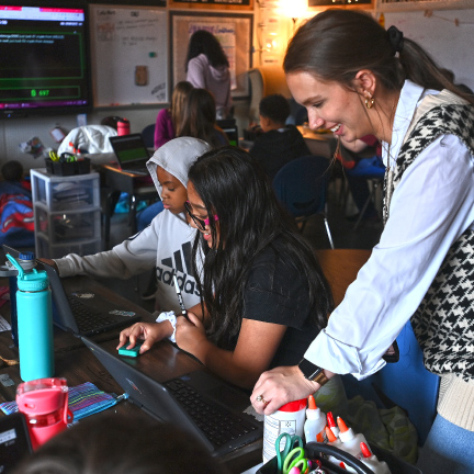 Students and teacher looking at a computer 