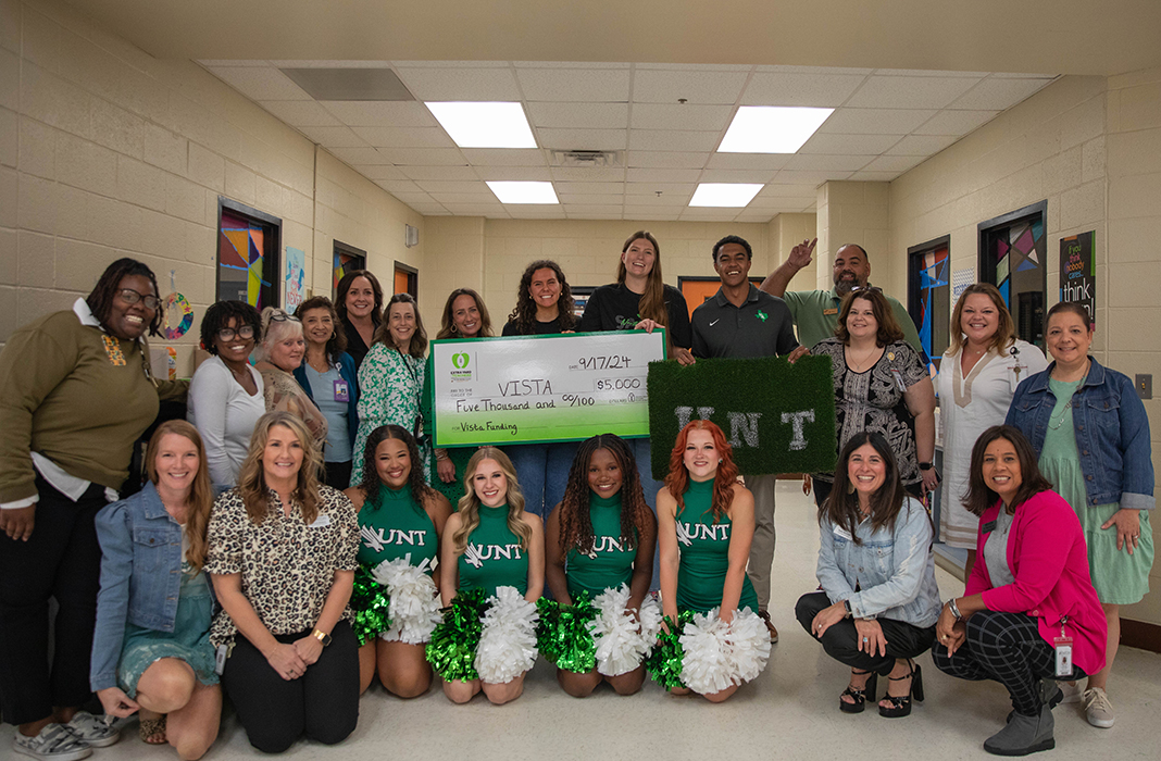 Students and staff pose with a check